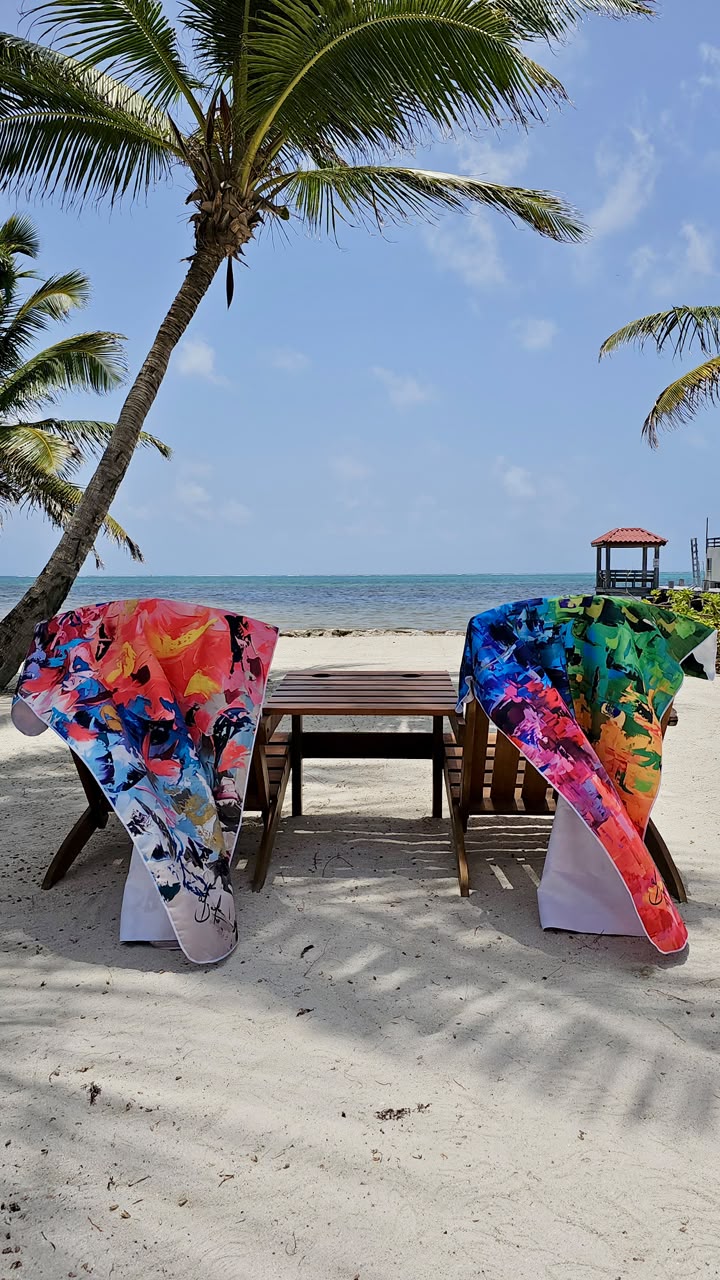 Los dos diseños de toallas, uno en tonos coral y otro multicolor, sobre sillas en la playa