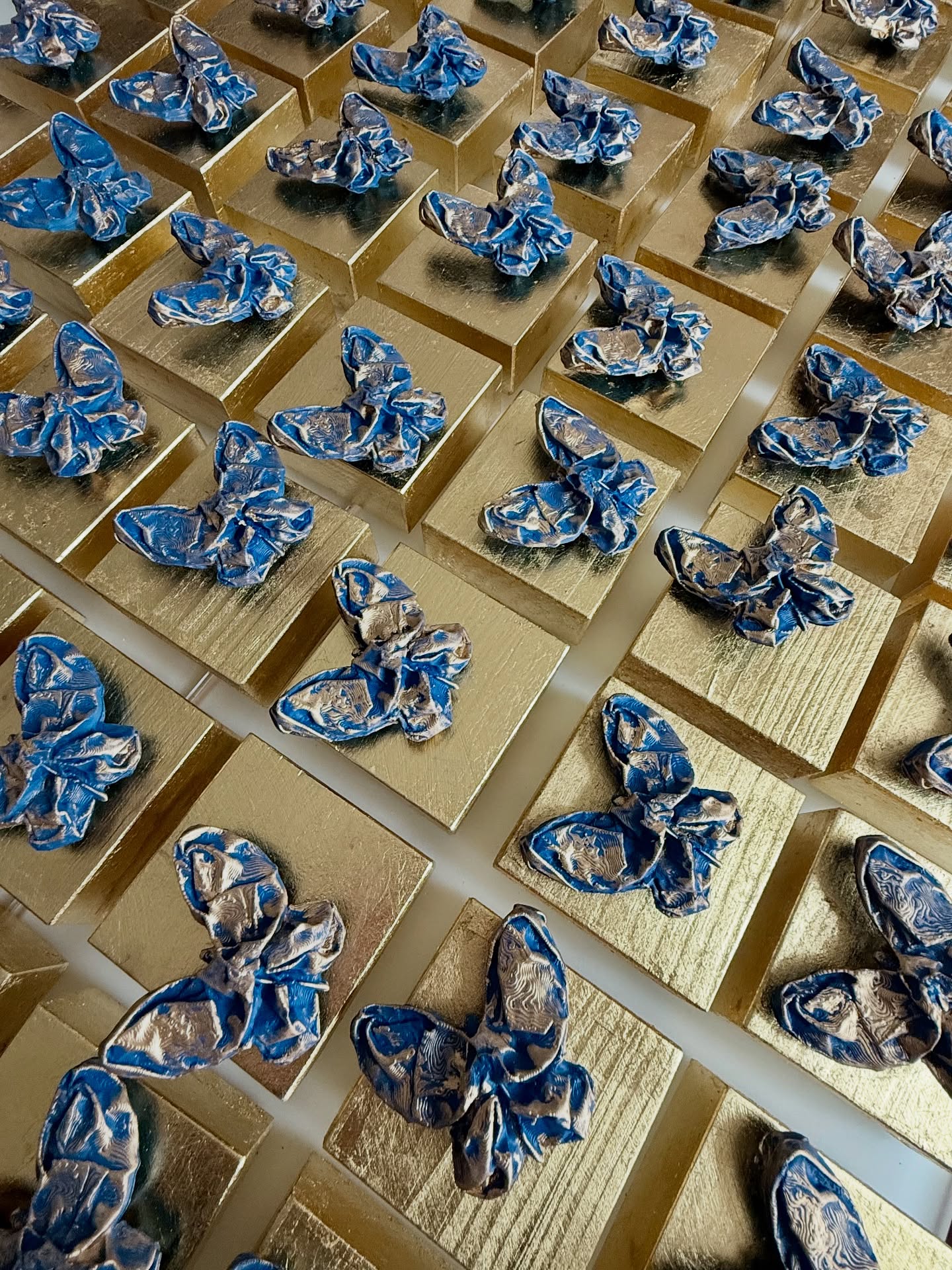 Ediciones de mariposas azules sobre bases doradas para regalos corporativos